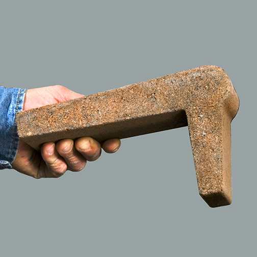 A pool Edge Coping held a man's hand, extended from blue work shirt. Photo background is a light blueish gray